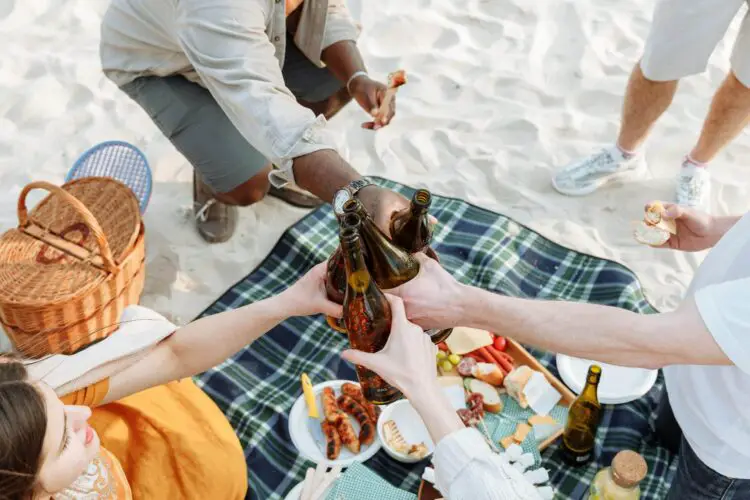 People celebrating with beer during a beach picnic